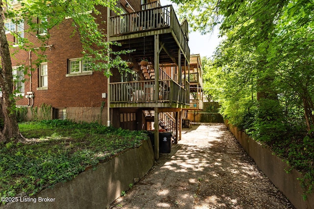 back of house featuring brick siding, stairway, and a deck