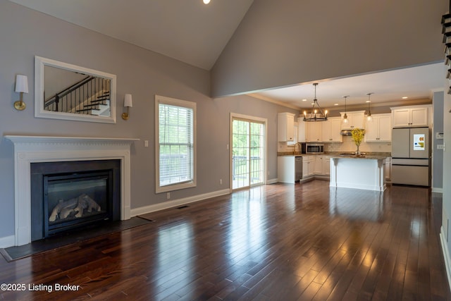 unfurnished living room with baseboards, a fireplace with flush hearth, and dark wood finished floors