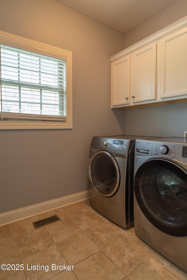 laundry room featuring cabinet space, separate washer and dryer, baseboards, and light tile patterned floors