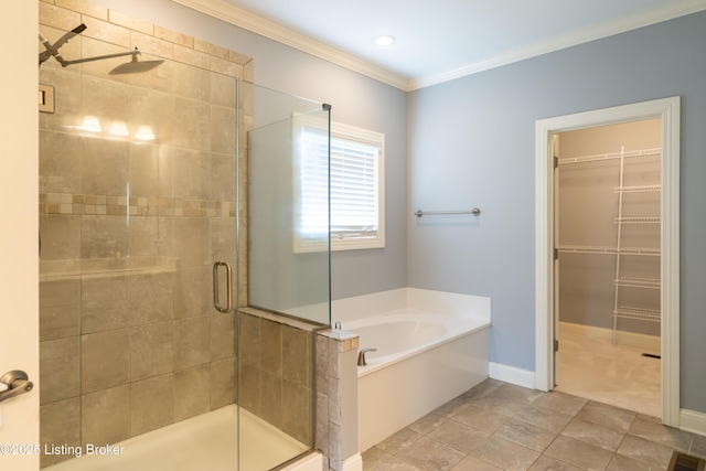 bathroom with a stall shower, a garden tub, crown molding, a walk in closet, and baseboards