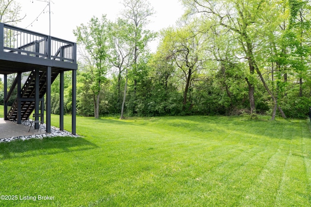 view of grassy yard featuring a wooden deck and stairway