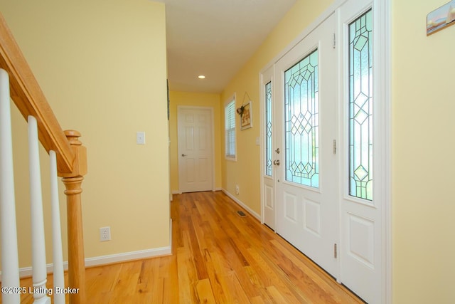 foyer featuring light wood finished floors, stairway, baseboards, and recessed lighting