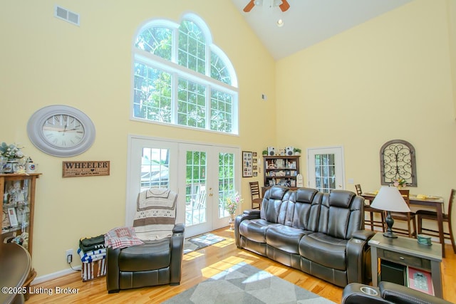 living area with high vaulted ceiling, french doors, a ceiling fan, wood finished floors, and baseboards
