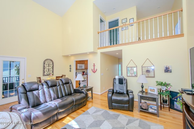 living area with a towering ceiling, wood finished floors, and baseboards