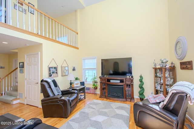 living area with a high ceiling, wood finished floors, stairway, and a fireplace