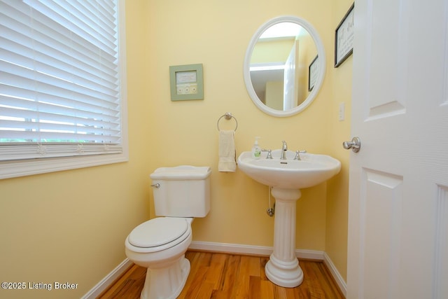 bathroom featuring wood finished floors, toilet, baseboards, and a sink