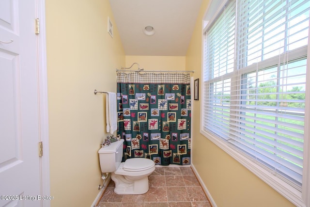 bathroom with baseboards, toilet, and curtained shower