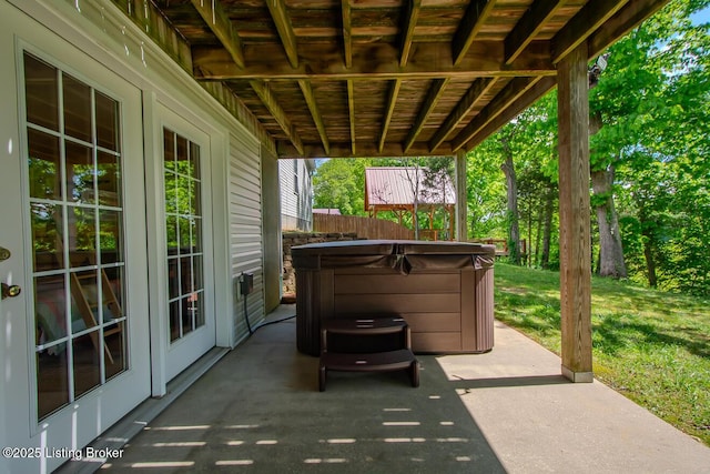 view of patio / terrace with a hot tub and fence