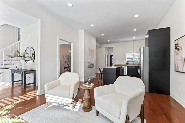 living area with recessed lighting, dark wood-type flooring, baseboards, and stairs