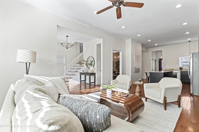 living room featuring stairway, ceiling fan with notable chandelier, recessed lighting, and light wood-style floors