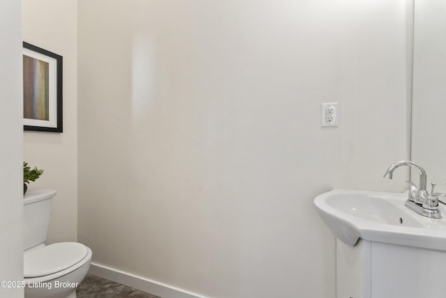bathroom featuring toilet, baseboards, and a sink