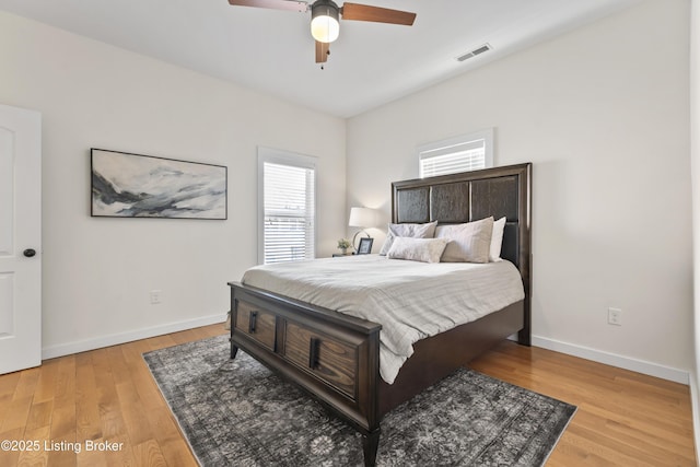 bedroom featuring light wood-style floors, visible vents, baseboards, and a ceiling fan