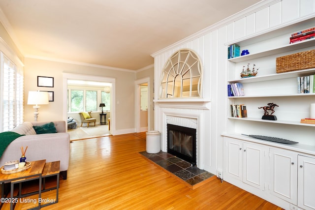 2104 Lauderdale Rd, Louisville, KY 40205 - living room with ornamental molding, built in shelves, light wood-style flooring, baseboards, and a tiled fireplace