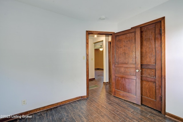 unfurnished room with baseboards, dark wood-style flooring, and a smoke detector