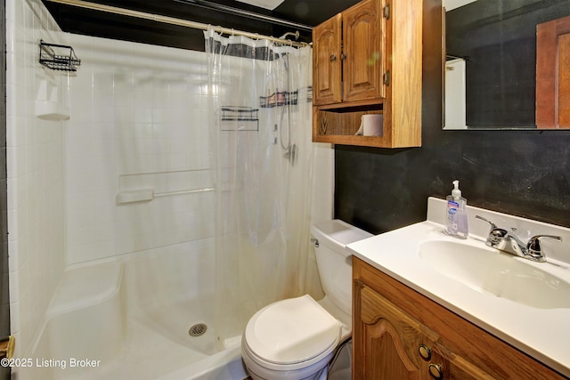 bathroom featuring toilet, a shower stall, and vanity
