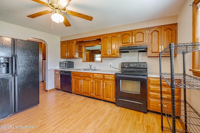 2213 Amboy Dr, Louisville, KY 40216 - kitchen featuring black appliances, a sink, under cabinet range hood, arched walkways, and light wood finished floors