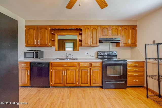 2213 Amboy Dr, Louisville, KY 40216 - kitchen with black appliances, under cabinet range hood, light wood finished floors, brown cabinetry, and a sink