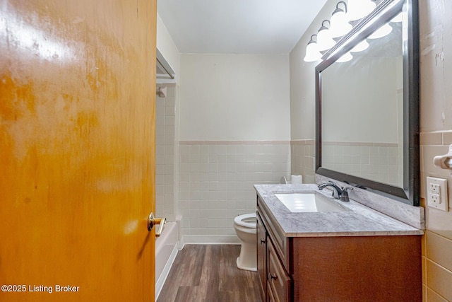 2213 Amboy Dr, Louisville, KY 40216 - bathroom with wood finished floors, toilet, tile walls, vanity, and wainscoting