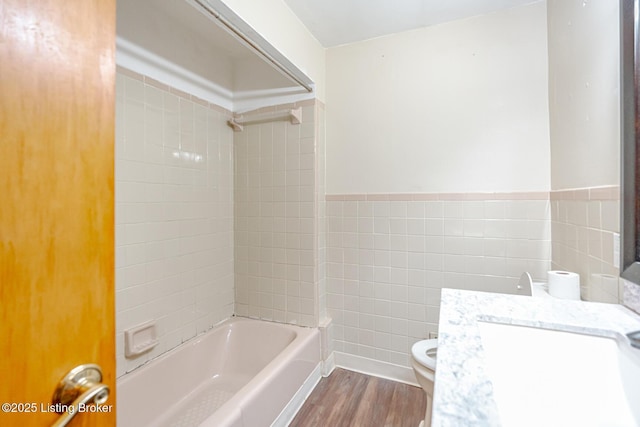 2213 Amboy Dr, Louisville, KY 40216 - bathroom with tile walls, wood finished floors, toilet, bathtub / shower combination, and a wainscoted wall
