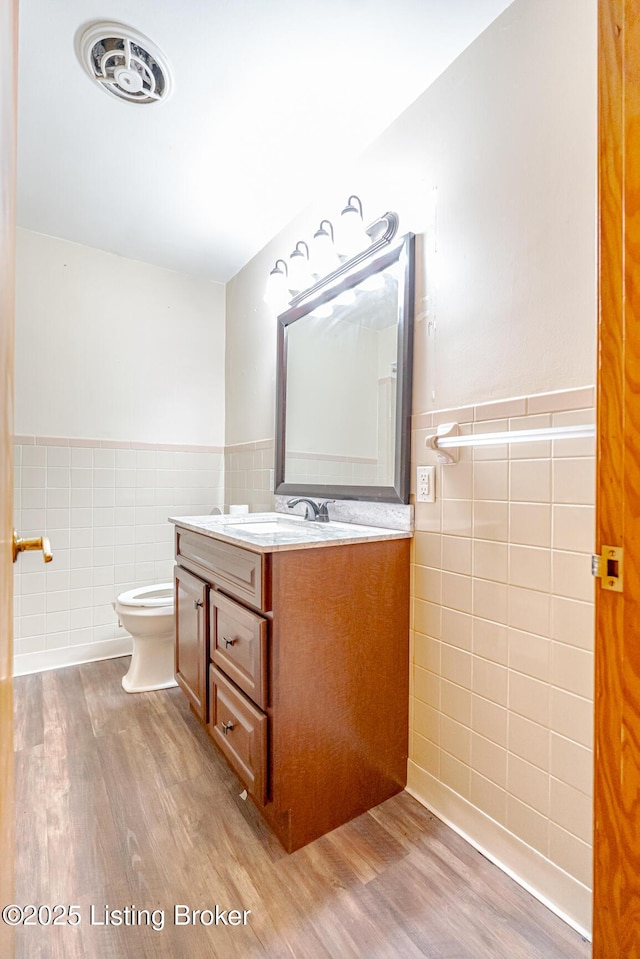 2213 Amboy Dr, Louisville, KY 40216 - half bathroom featuring tile walls, wood finished floors, wainscoting, vanity, and toilet