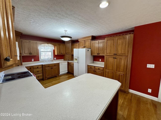 kitchen with light countertops, wood finished floors, a sink, and white appliances