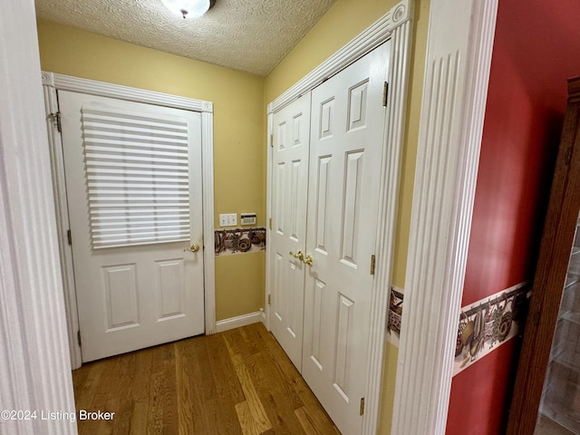 doorway to outside with baseboards, a textured ceiling, and wood finished floors