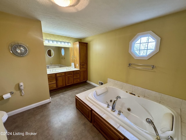 full bath featuring a whirlpool tub, a textured ceiling, visible vents, baseboards, and vanity
