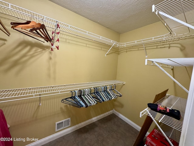 spacious closet with dark colored carpet and visible vents