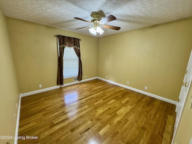 spare room featuring a textured ceiling, wood finished floors, baseboards, and ceiling fan