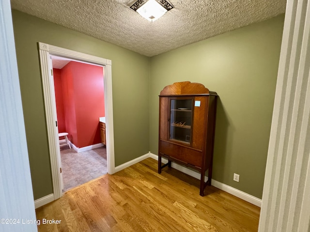 interior space with a textured ceiling, baseboards, and wood finished floors