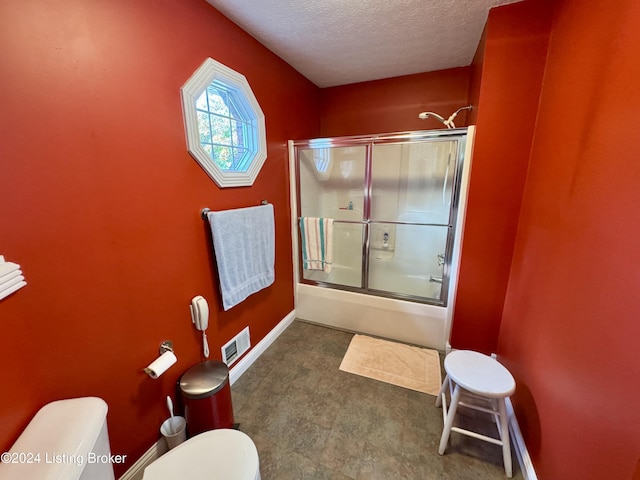 bathroom with toilet, shower / bath combination with glass door, a textured ceiling, visible vents, and baseboards