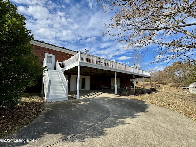 exterior space featuring stairway, concrete driveway, a carport, and a deck