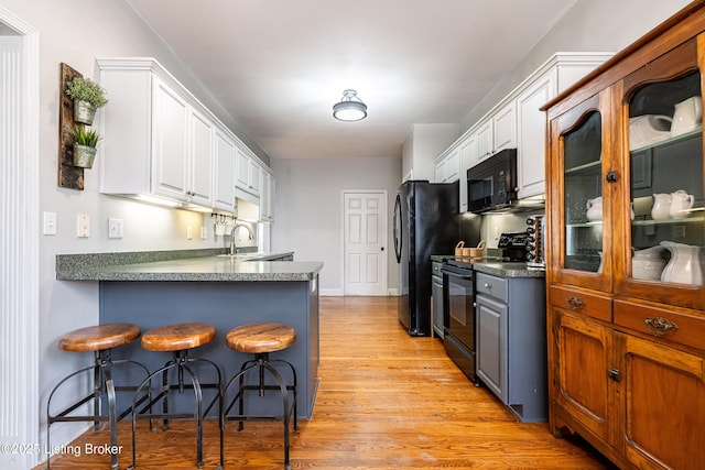 13216 Willow Forest Dr, Louisville, KY 40245 - kitchen with black appliances, white cabinetry, a kitchen bar, and light wood-type flooring