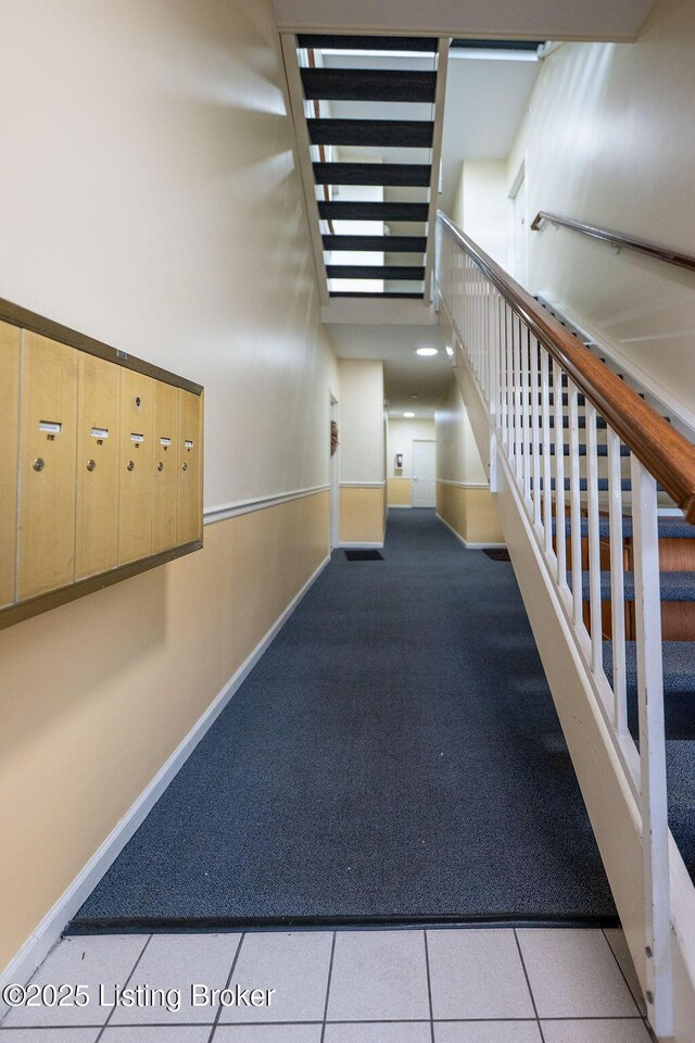 hall with a towering ceiling, baseboards, and mail area