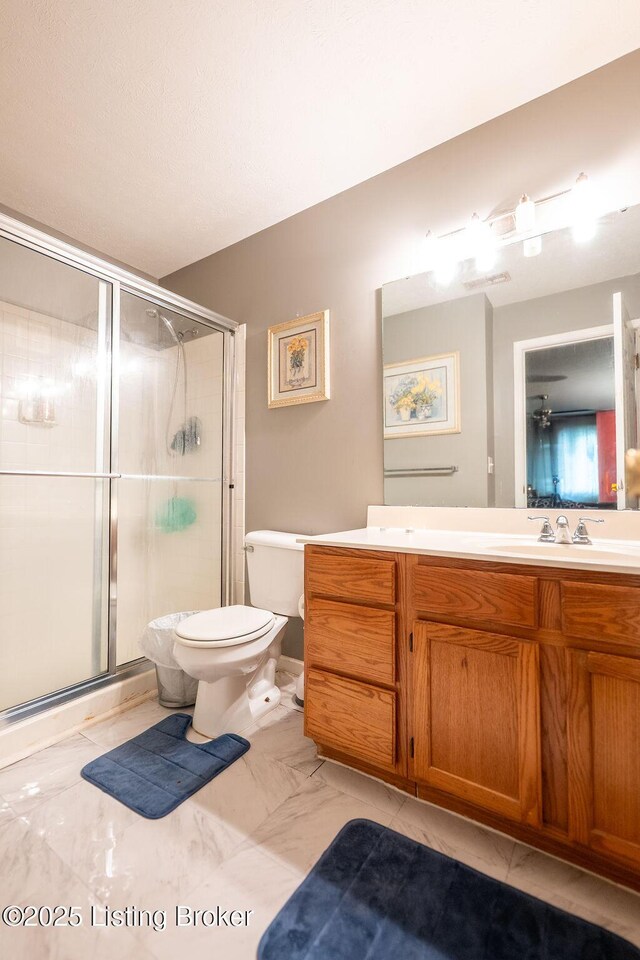 bathroom featuring a shower stall, vanity, toilet, and marble finish floors