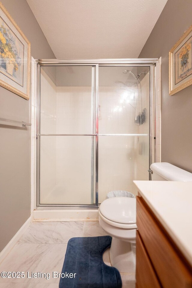 full bathroom featuring toilet, marble finish floors, a shower stall, and vanity