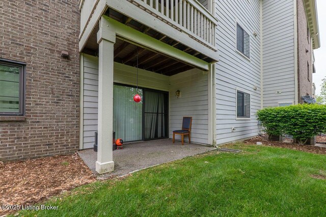 entrance to property featuring a lawn and brick siding