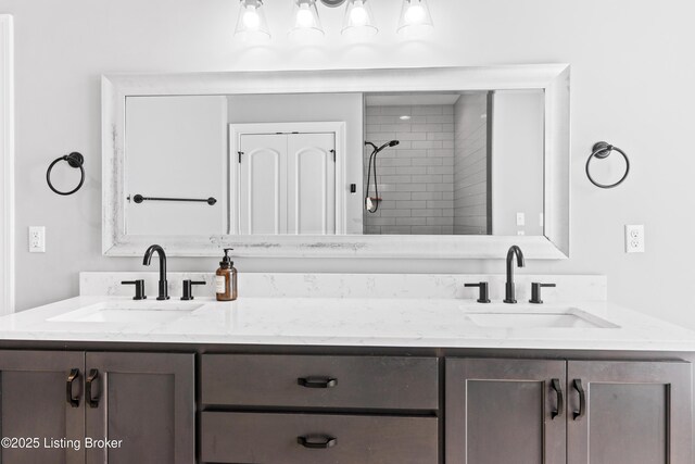 full bath featuring double vanity and tiled shower