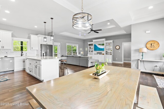 dining area featuring a tray ceiling, recessed lighting, ceiling fan, dark wood finished floors, and a chandelier