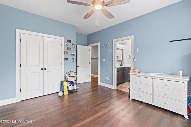 bedroom featuring a sink, dark wood-style flooring, a closet, baseboards, and a ceiling fan