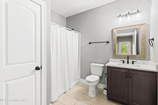 bathroom with toilet, vanity, baseboards, and a shower with curtain