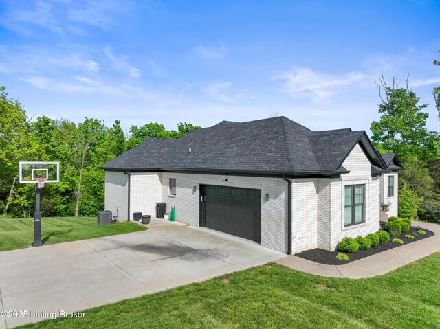 view of side of home featuring an attached garage, concrete driveway, a yard, brick siding, and roof with shingles