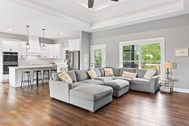 living room with a ceiling fan, recessed lighting, dark wood-type flooring, crown molding, and a raised ceiling