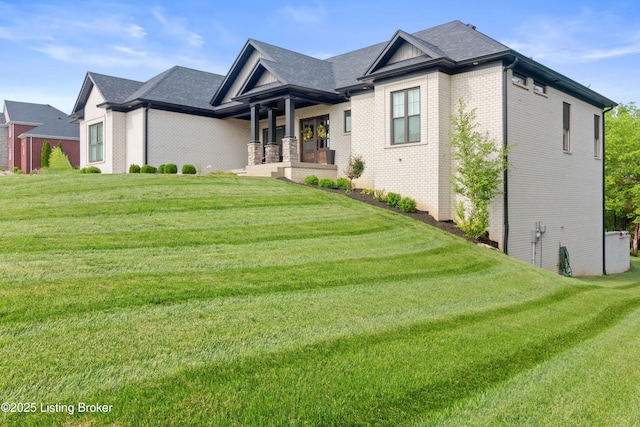 view of front of property featuring brick siding, a front yard, and covered porch