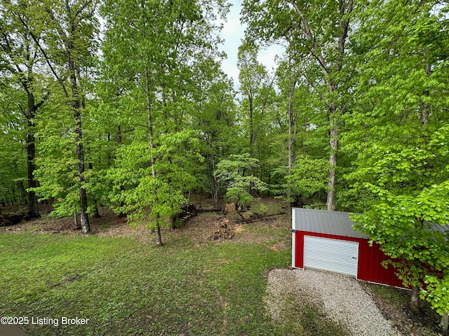 view of yard featuring gravel driveway, an outbuilding, and a garage