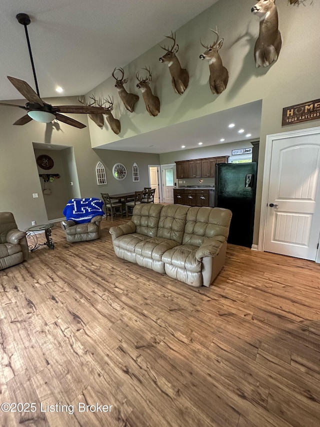 living area with ceiling fan, high vaulted ceiling, and wood finished floors