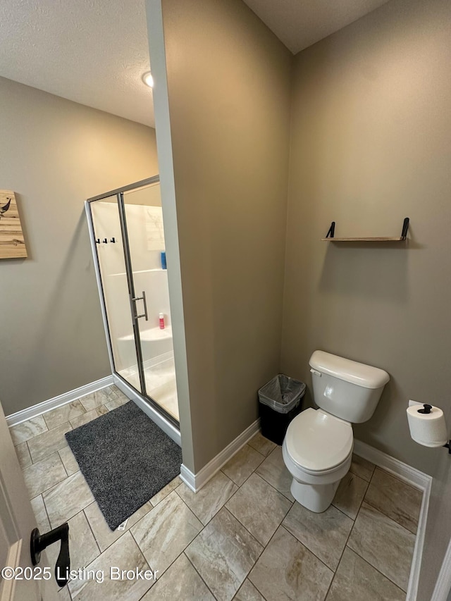 full bathroom featuring toilet, baseboards, and a shower stall