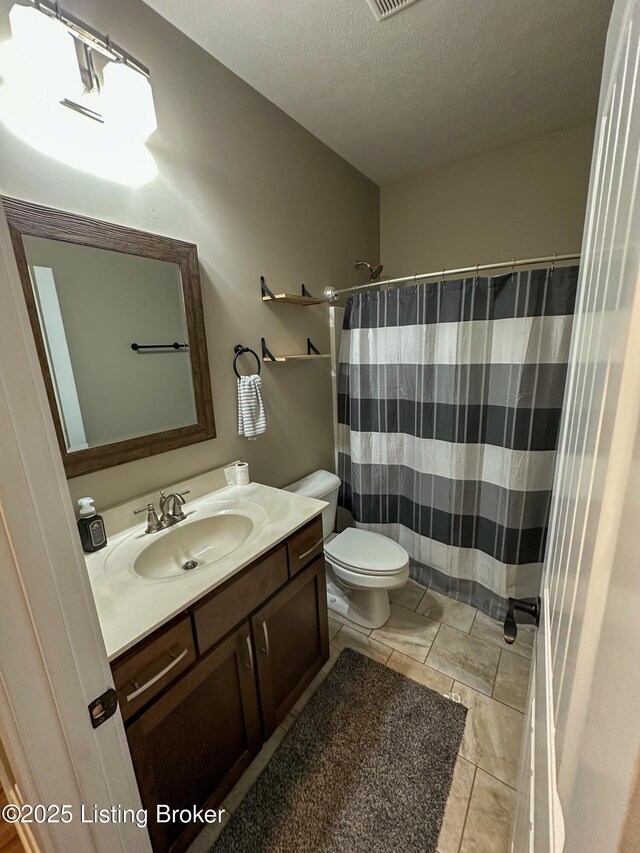 bathroom featuring toilet, a shower with shower curtain, a textured ceiling, tile patterned flooring, and vanity