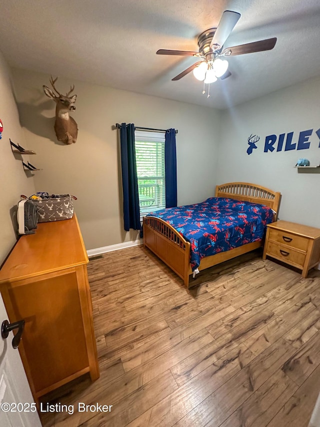 bedroom with a ceiling fan, baseboards, and wood-type flooring