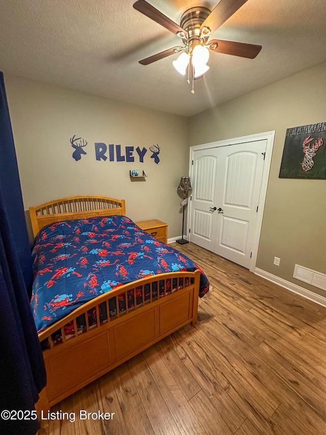 bedroom featuring a textured ceiling, wood finished floors, baseboards, and ceiling fan